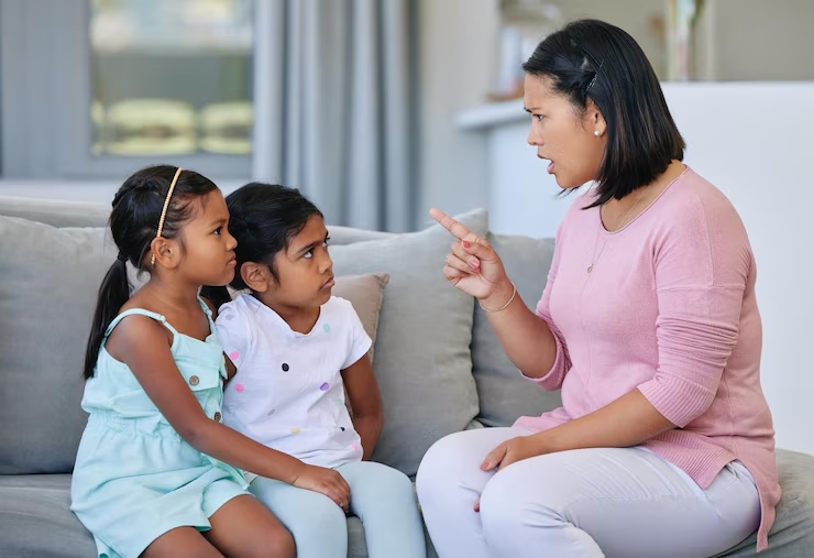 a mother talking firmly to her two daughters at home
