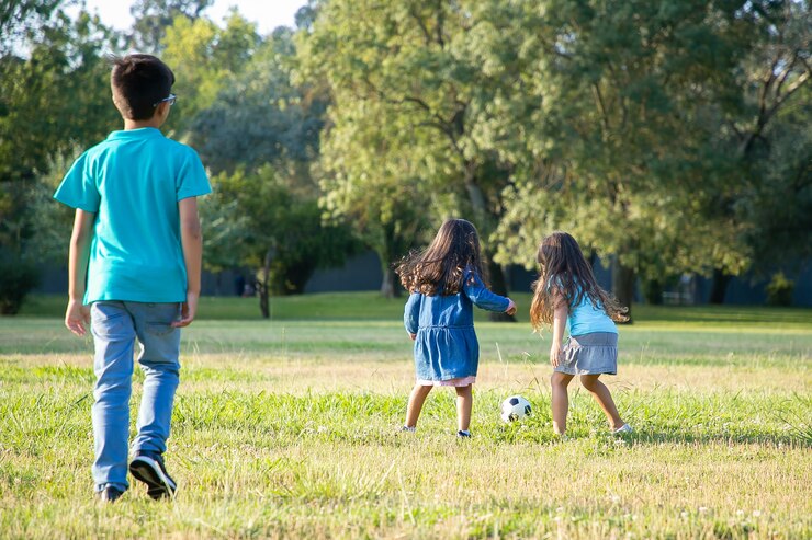 children playing football on grass in a city park